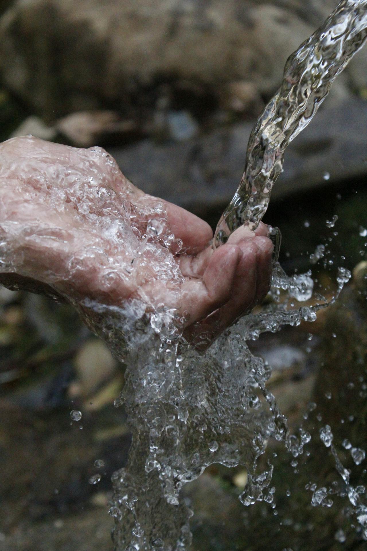 person cleaning hands under clear water